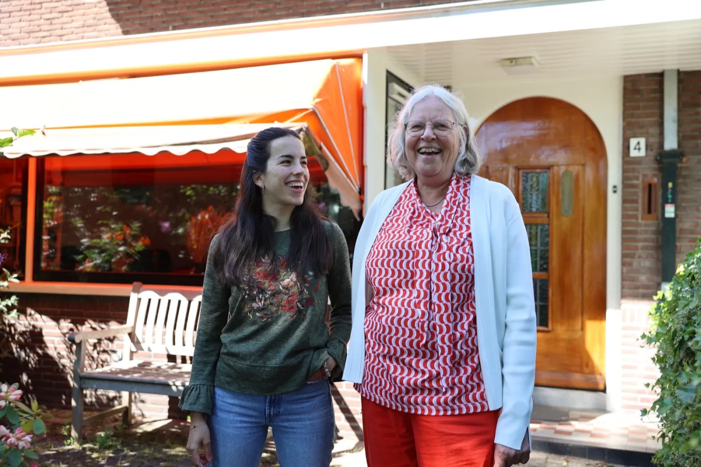 Een hospita en huurder lachend in de deuropening van hun huis